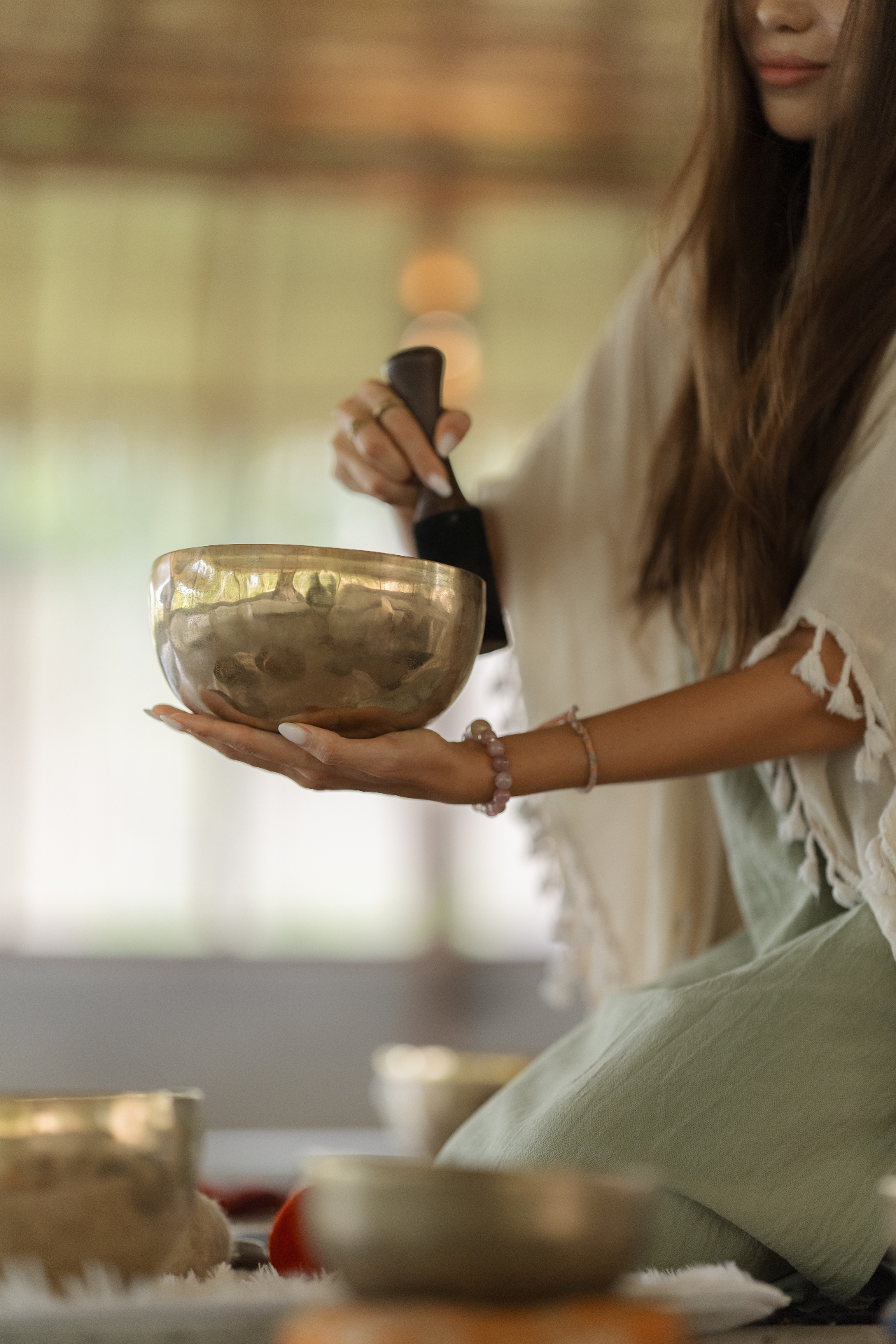 Warm interior of the shala — singing bowls held in hand